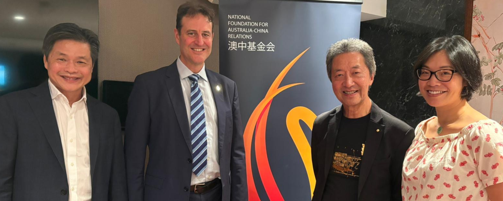 4 people standing next to a banner 